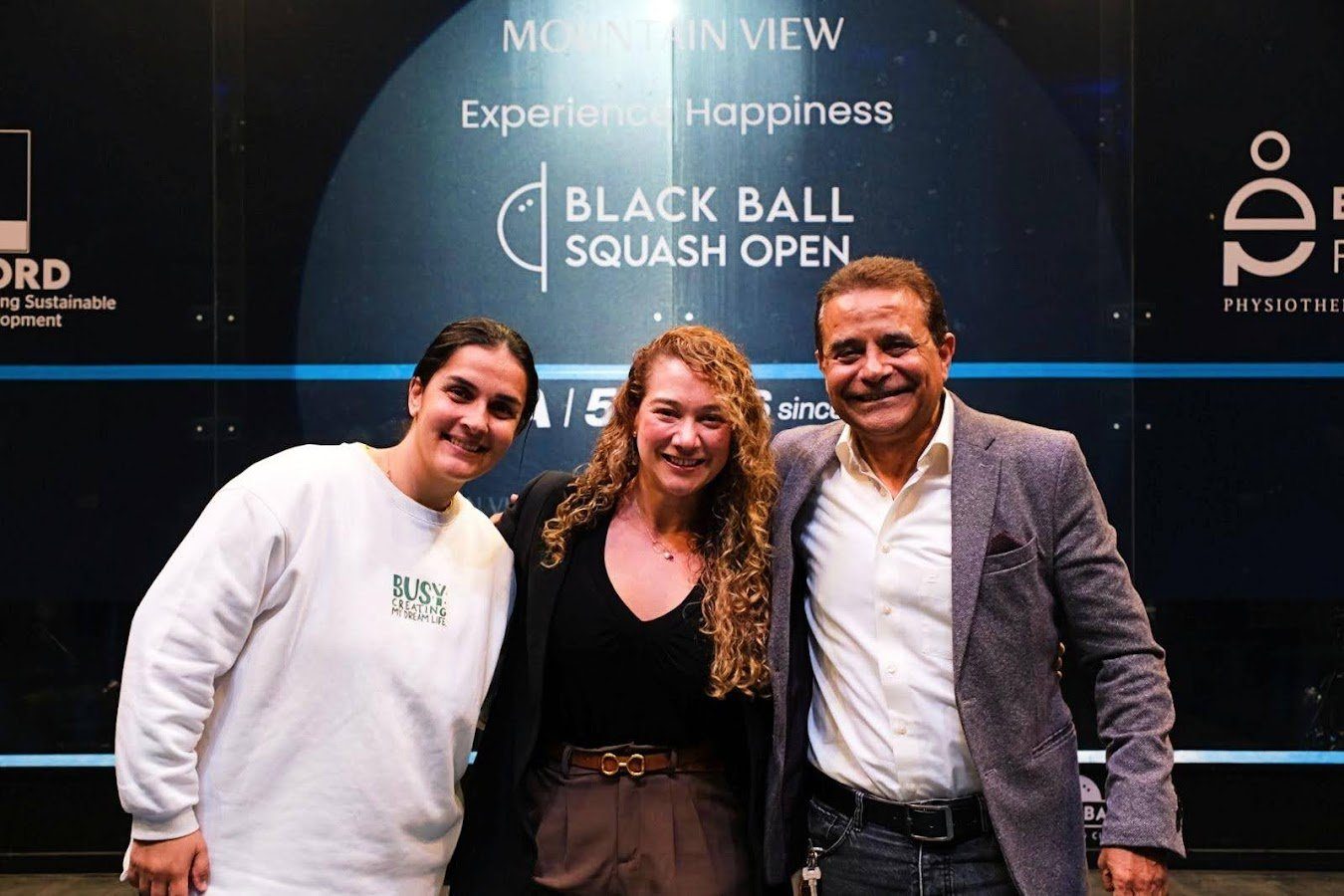 Photo shows Ashraf Hanafi at Black Ball Squash Open 2024 with Adriana Olaya, Head of PSA Foundation (middle), and Omneya Abdel Kawy