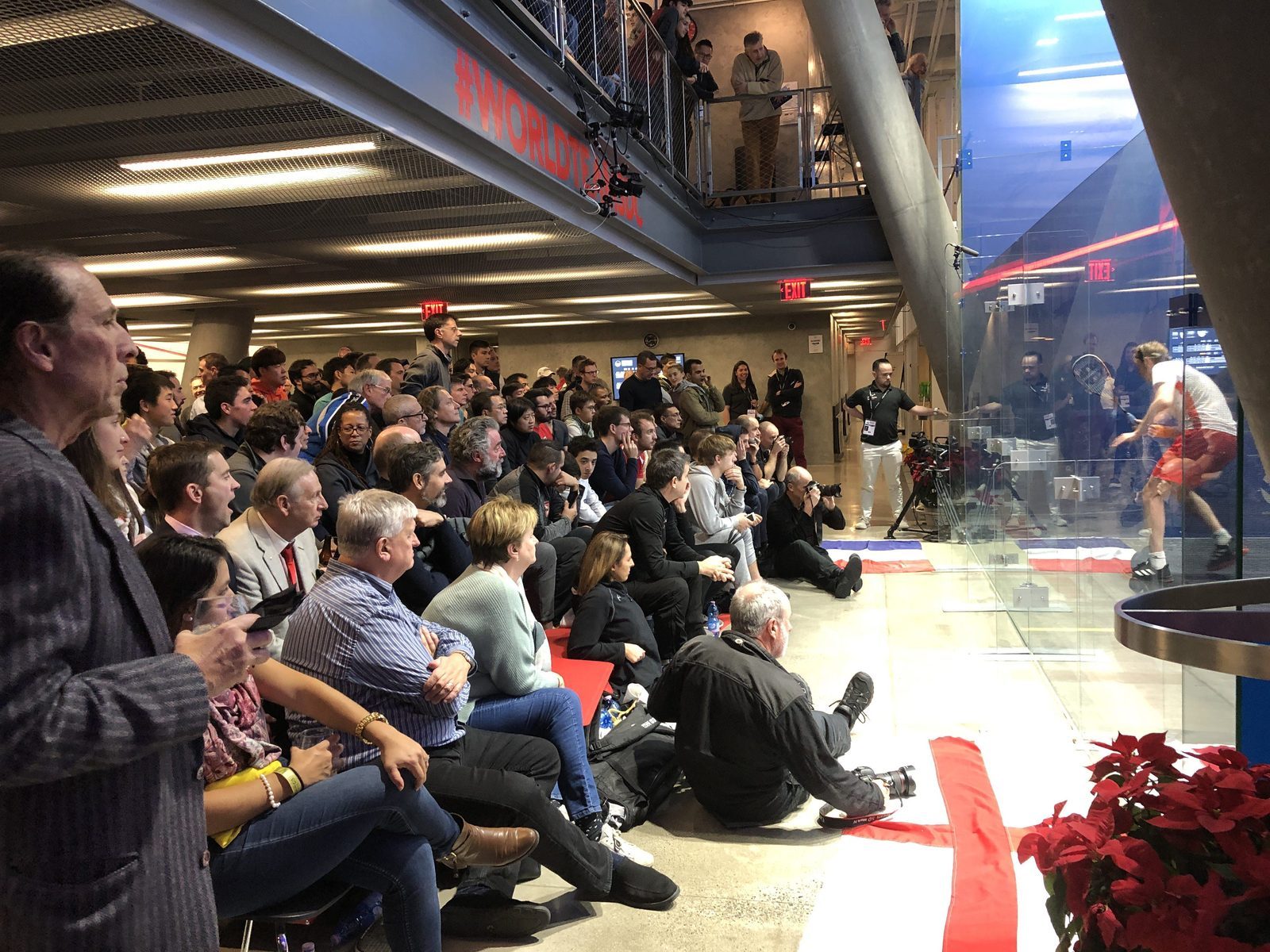 The phot shows many spectators following action during the PSA World Tour event