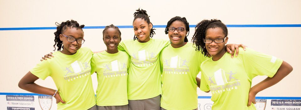 five girls smilling on a squash court
